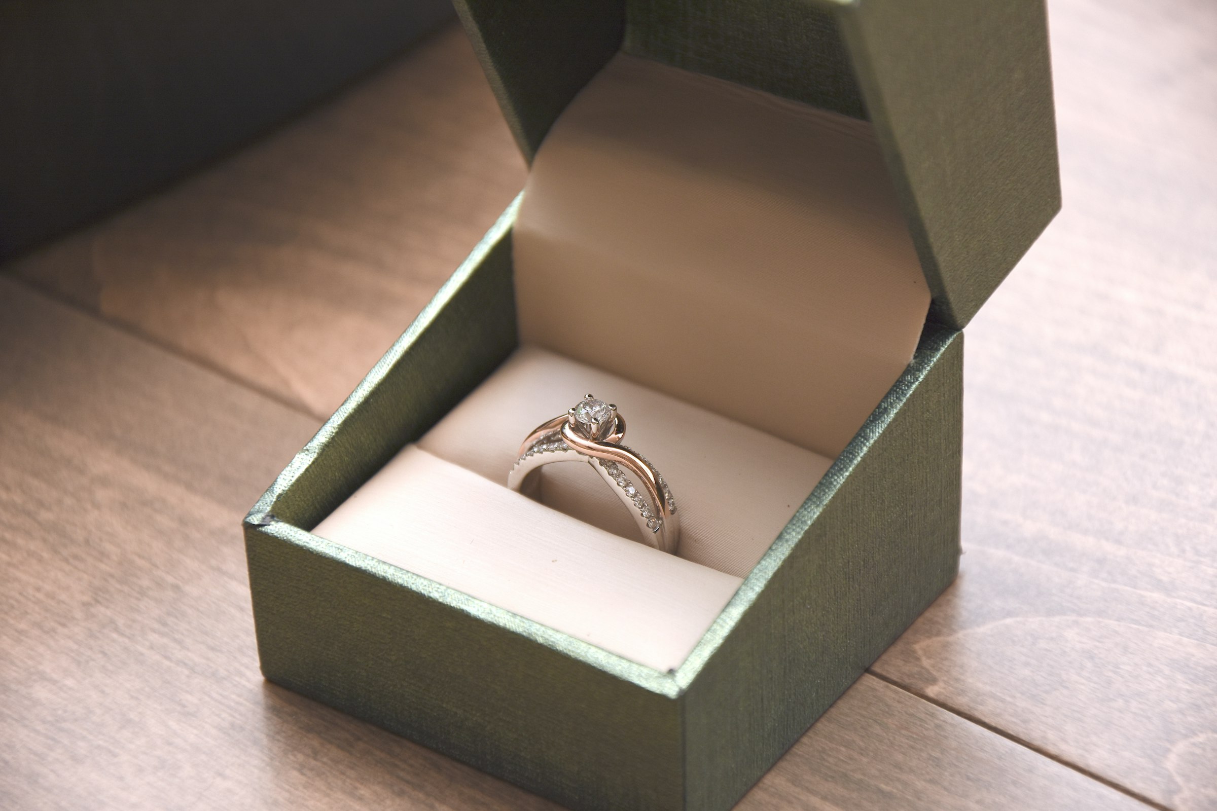 Hands presenting a diamond ring in a lit box